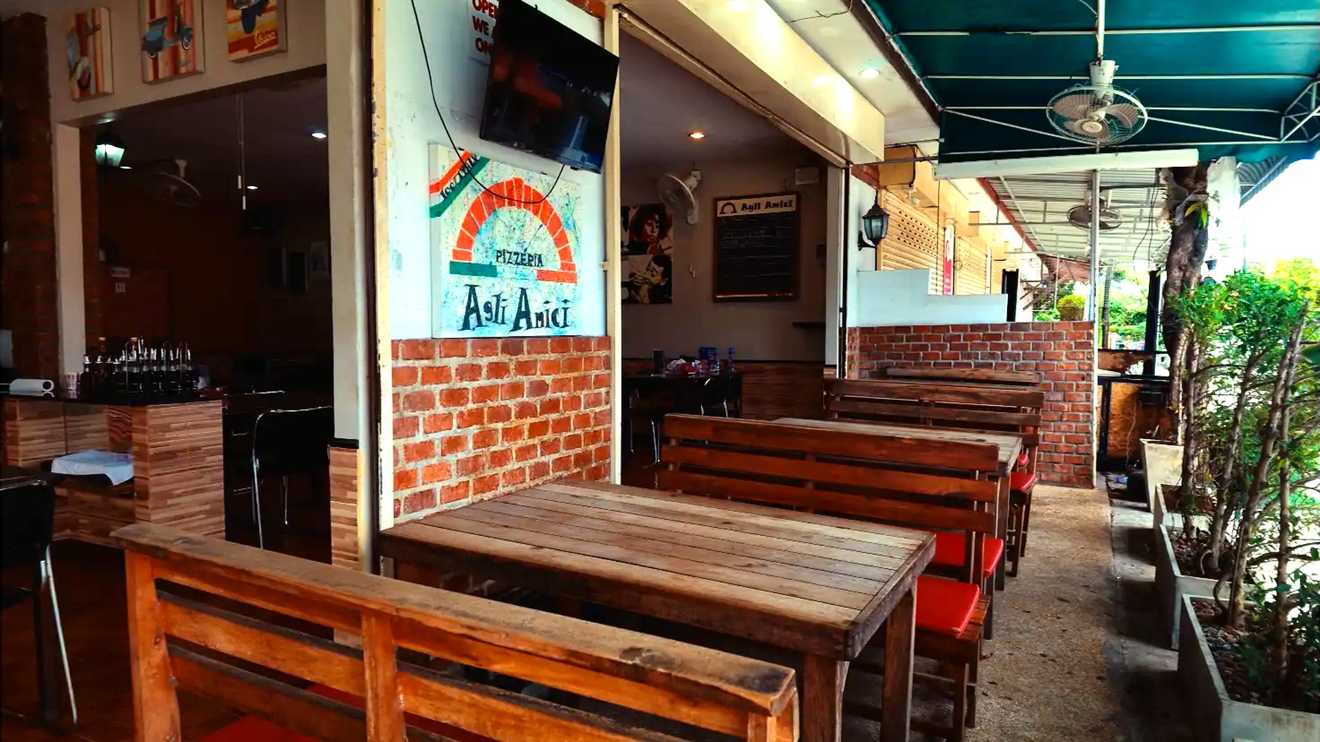 Wooden tables and brick walls on the terrace at Agli Amici Phuket in Chalong